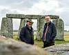 Bildet av Phil Harding med langt grått hår og en hatt på hodet, og Matt Leivers med grått hår og briller. Begge har blå jakker og står foran deler av Stonehenge. Himmelen bak er grå.