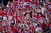 Tettpakket tribune med supportere i rødt, hvitt og blått som applauderer og vifter med skjerf.