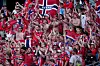 Tettpakket tribune med supportere i rødt, hvitt og blått som applauderer og vifter med skjerf.