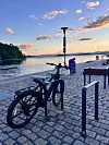Sykkel parkert på brygge ved vannet under solnedgang.