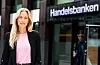 En kvinne står foran en bankinngang med Handelsbanken-skilt i bakgrunnen.
