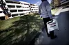 Person går langs fortauet foran en boligblokk og bærer et skilt med teksten «Visning».