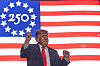 Donald Trump står foran et stort amerikansk flagg og hever hånden etter en tale.