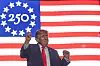 Donald Trump står foran et stort amerikansk flagg og hever hånden etter en tale.