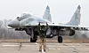 Ukrainsk MiG-29 jagerfly parkert på en rullebane, med en soldat foran flyet.