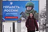 En kvinne går forbi en billboard med en russisk soldat og russisk tekst i St. Petersburg.