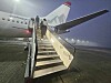 Passasjerfly på flyplass med trapp opp til døren i tåke.
