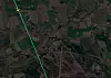 Satellittbilde av åkre, skog og spredt bebyggelse med en vei som går på skrå gjennom området.