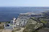 Oversiktsbilde av havneanlegg og industriområde ved kysten med kaier, bygg og sjø.