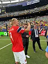Erling Barut Haaland i rød drakt vinkler til tilskuere på gressmatte foran fullsatt tribune.