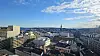 Panoramautsikt over bygninger, havn og vann under delvis skyet himmel.