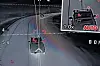 Skjermbilde fra et kontrollrom med dronekamera som følger et kjøretøy på en vei om natten.