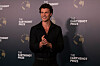 Shawn Mendes i svart antrekk poserer foran en vegg med Earthshot Prize-logoer.