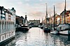 Båter langs en kanal med bygninger på begge sider under en lys himmel.
