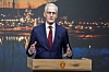 Statsminister Jonas Gahr Støre taler fra talerstol foran et nattlig bymotiv.