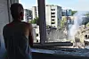 En mann ser på røyk og ruiner ved en skadet boligblokk i Lviv etter et luftangrep.