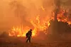 En brannmann står foran store flammer i et røykfylt landskap under Canyon-brannen i California.