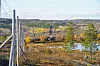Gjerde i forgrunnen med utsikt over skog, vann og høstfargede åser ved Jarfjord grensestasjon.