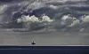 Kvitebjørn-plattformen sees som en liten silhuett på havet under dramatiske skyer.