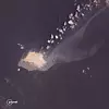 Satellittbilde av et grunnstøtt tankskip med en lys oljeflekk som sprer seg i havet.