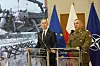 To polske forsvarstopper står ved talerstoler foran EU-, Polen- og NATO-flagg i Warszawa.