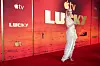 Anya Taylor-Joy i hvit kjole på rød løper foran en «Lucky»-bakgrunn med Apple TV+-logoer.