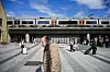 En mann går over plassen foran Skøyen stasjon mens flere passasjerer venter ved perrongområdet.