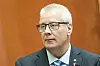 En mann i dress står foran en oransje vegg under en pressekonferanse på Stortinget.