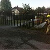 Brannmann med slange sprøyter vann mot røyk i et område nær trær og en bolig.