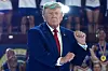Donald Trump står foran et publikum innendørs og holder en knyttet hånd opp ved tribunen.