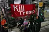 Kvinner sitter foran et rødt banner med teksten «Kill Trump» i en gate i Teheran.