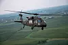 UH-60 Black Hawk-helikopter flyr over grønne jorder i landlig område.