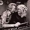 To personer smiler til hverandre ved et lydmiksbord i et studio.