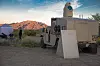 Et militært kjøretøy med laserutstyr står ved en ørkenflyplass med fjell i bakgrunnen.