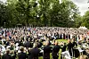 Stor folkemengde samlet til hagefest i en grønn park med musikere i forgrunnen.