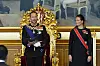 Kong Haakon VIII sitter på en utsmykket tronstol, mens kronprinsesse Ingrid Alexandra står ved siden av i Stortinget.