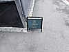 Et grønt ståskilt med Norvia-logo står på asfalten ved en murvegg.