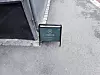 Et grønt ståskilt med Norvia-logo står på asfalten ved en murvegg.