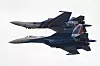 To Sukhoi Su-35S-jagerfly flyr tett sammen mot lys himmel under en flyoppvisning.