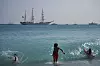 Svømmere i forgrunnen med seilskip ute på havet ved Nice under Ocean Wonders.