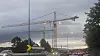 Stor byggekraan over en trafikkert vei i gråvær ved skumring.
