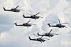 Fem russiske militærhelikoptre flyr i formasjon mot en lys himmel.