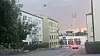Bygate med boligblokker, trær, biler og rosa kveldshimmel.