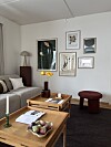 Lys stue med sofa, salongbord, kunst på veggene og dekorative møbler.