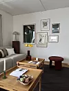 Lys stue med sofa, salongbord, kunst på veggene og dekorative møbler.