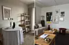 Lys stue med sofa, salongbord, spisebord, planter, kunst på veggene og dekorative tekstiler.