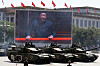 Kinesiske stridsvogner kjører i parade foran en stor skjerm med Xi Jinping i Beijing.
