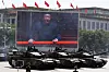 Kinesiske stridsvogner kjører i parade foran en stor skjerm med Xi Jinping i Beijing.