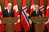 Mark Carney og Jonas Gahr Støre taler fra hver sin talerstol foran canadiske og norske flagg.