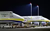 To store Antonov-fraktfly står side ved side på en opplyst flyplass om natten.